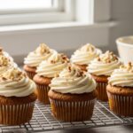 Cream cheese frosted carrot cupcakes on cooling rack